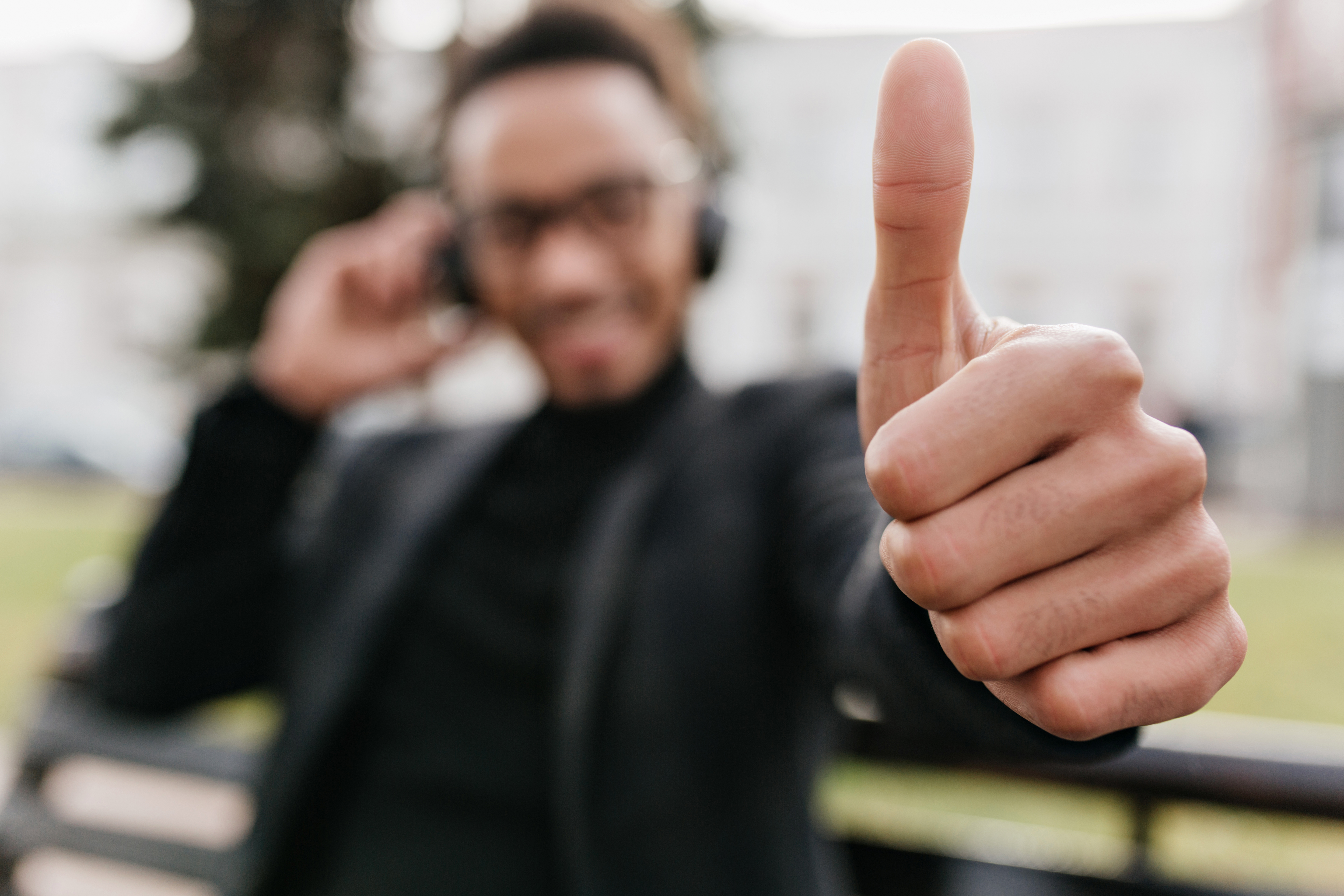 blur-portrait-african-smiling-guy-with-his-hand-focus-relaxed-black-man-elegant-suit-sitting-bench-showing-thumb-up